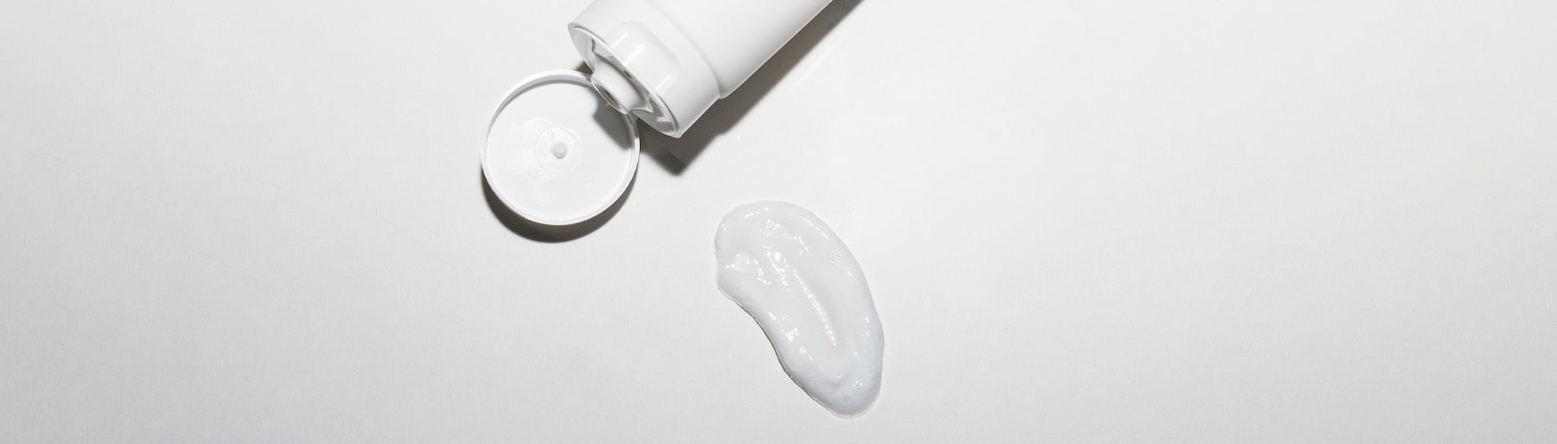 open cap of the hydrating cleanser bottle and a smear of the cleanser cream