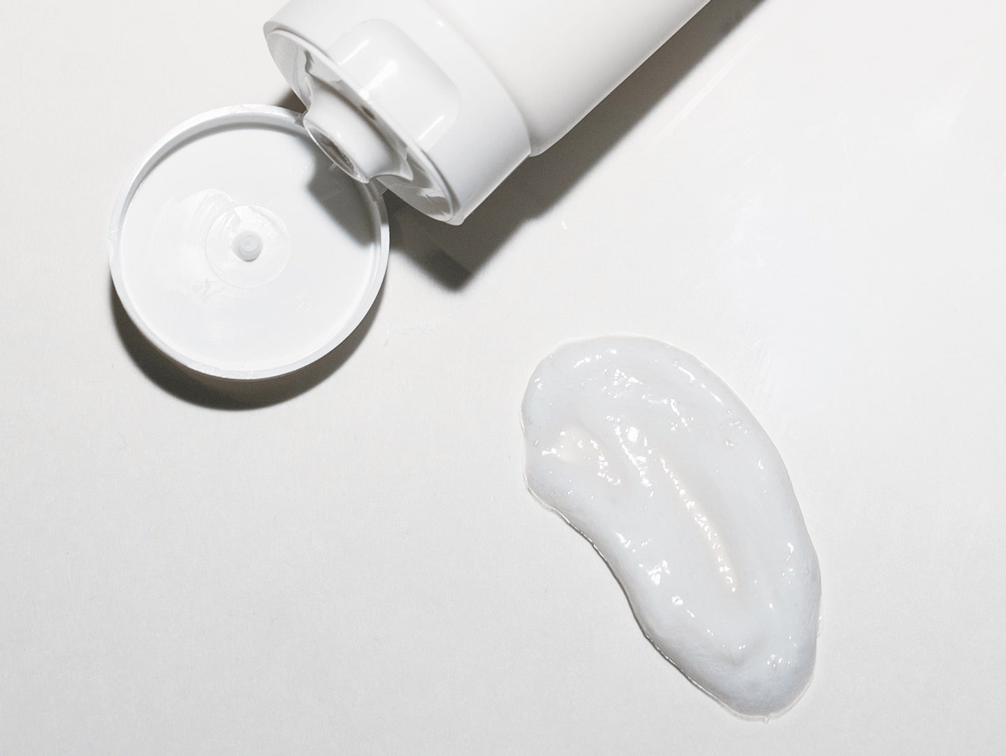 open cap of the hydrating cleanser bottle and a smear of the cleanser cream