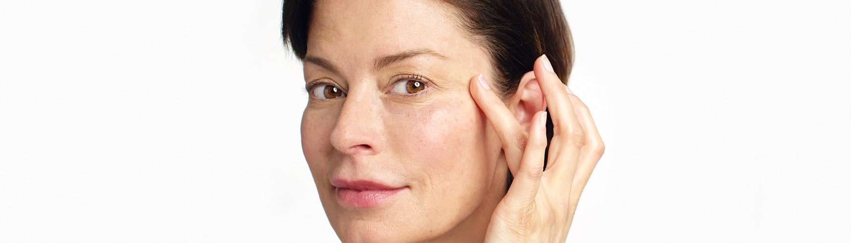close up photo of a woman with brown hair applying the moisture lock hydrator to her eye wrinkles
